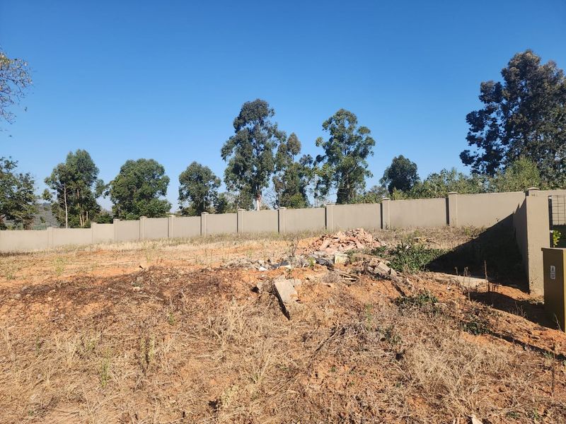 A vacant residential plot featuring a perimeter boundary wall and concrete pillars, currently requiring site clearing and landscaping.