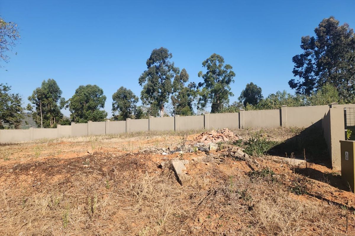 A vacant residential plot featuring a perimeter boundary wall and concrete pillars, currently requiring site clearing and landscaping.