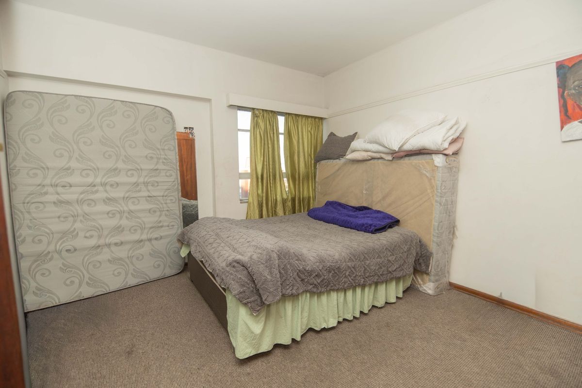 A bedroom featuring carpet flooring and a picture rail, currently requiring cosmetic updates to improve its overall condition and appeal.
