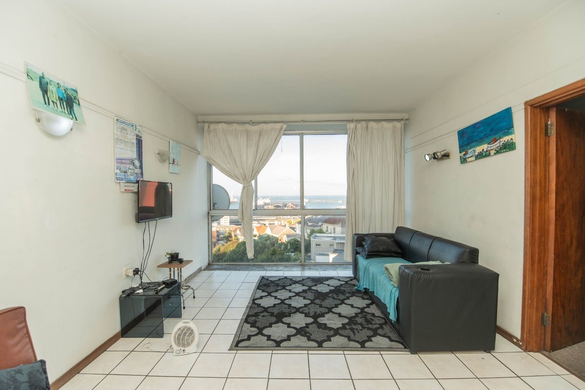 A living room featuring tiled flooring and a large window with views, offering a bright space ready for modernization and updated finishes.