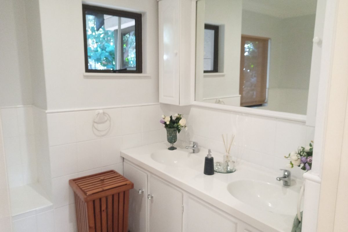 A clean, functional bathroom featuring a double vanity with integrated sinks, ample built-in cabinetry, and a large wall-mounted mirror.