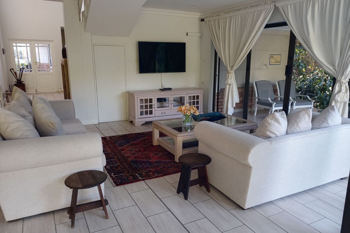 Spacious living room featuring light-toned tiled flooring, a staircase, and large sliding glass doors that provide seamless access to the outdoor patio area.
