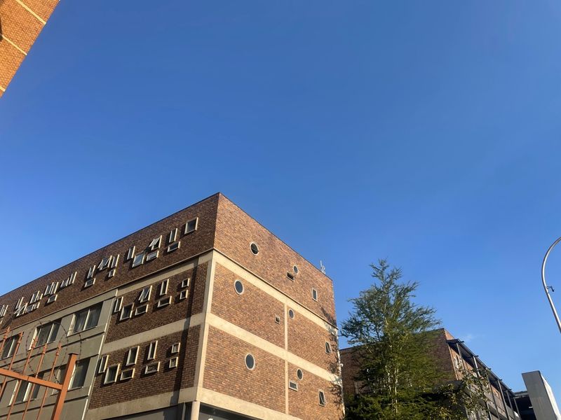 Exterior view of a multi-story apartment building featuring a distinctive brick facade with circular and rectangular window detailing.