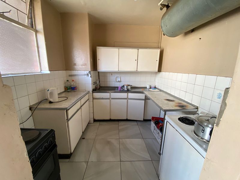 A dated kitchen featuring original cabinetry, tiled splashbacks, and tiled flooring, requiring modernization to improve functionality and aesthetic appeal.
