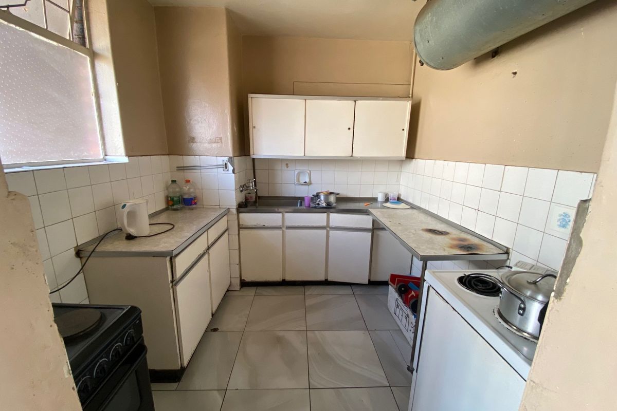 A dated kitchen featuring original cabinetry, tiled splashbacks, and tiled flooring, requiring modernization to improve functionality and aesthetic appeal.