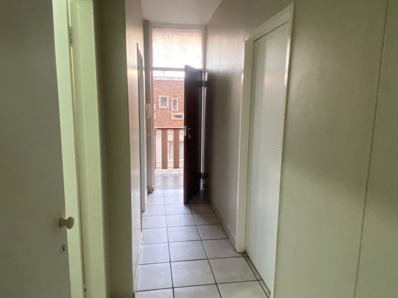 A functional apartment hallway featuring tiled flooring and access to an outdoor balcony area.