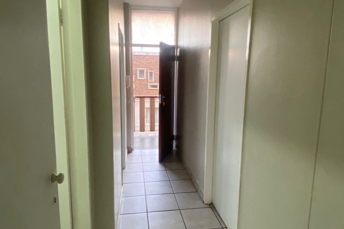 A functional apartment hallway featuring tiled flooring and access to an outdoor balcony area.