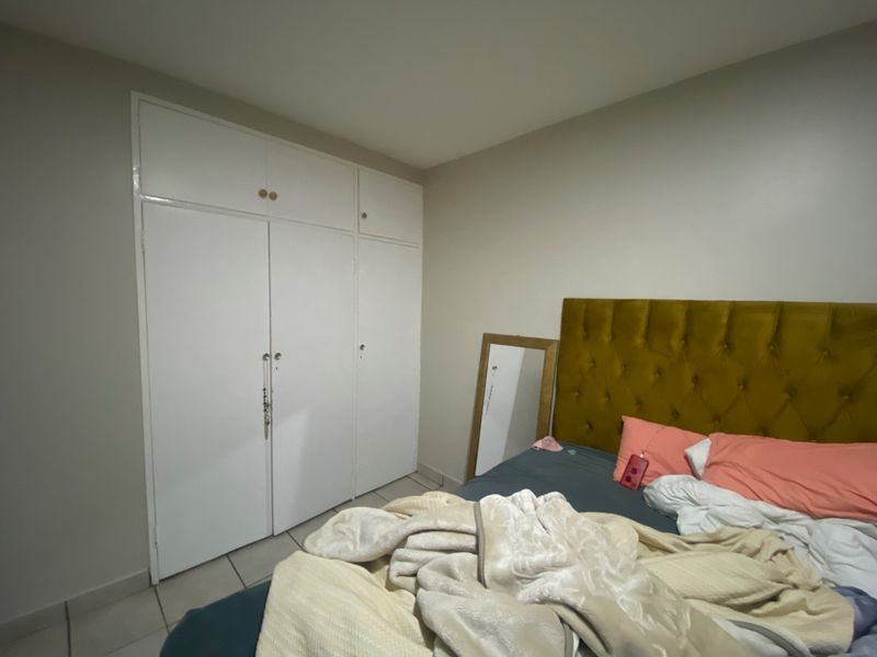 A bedroom featuring built-in cupboards and tiled flooring, providing functional storage space within the room.
