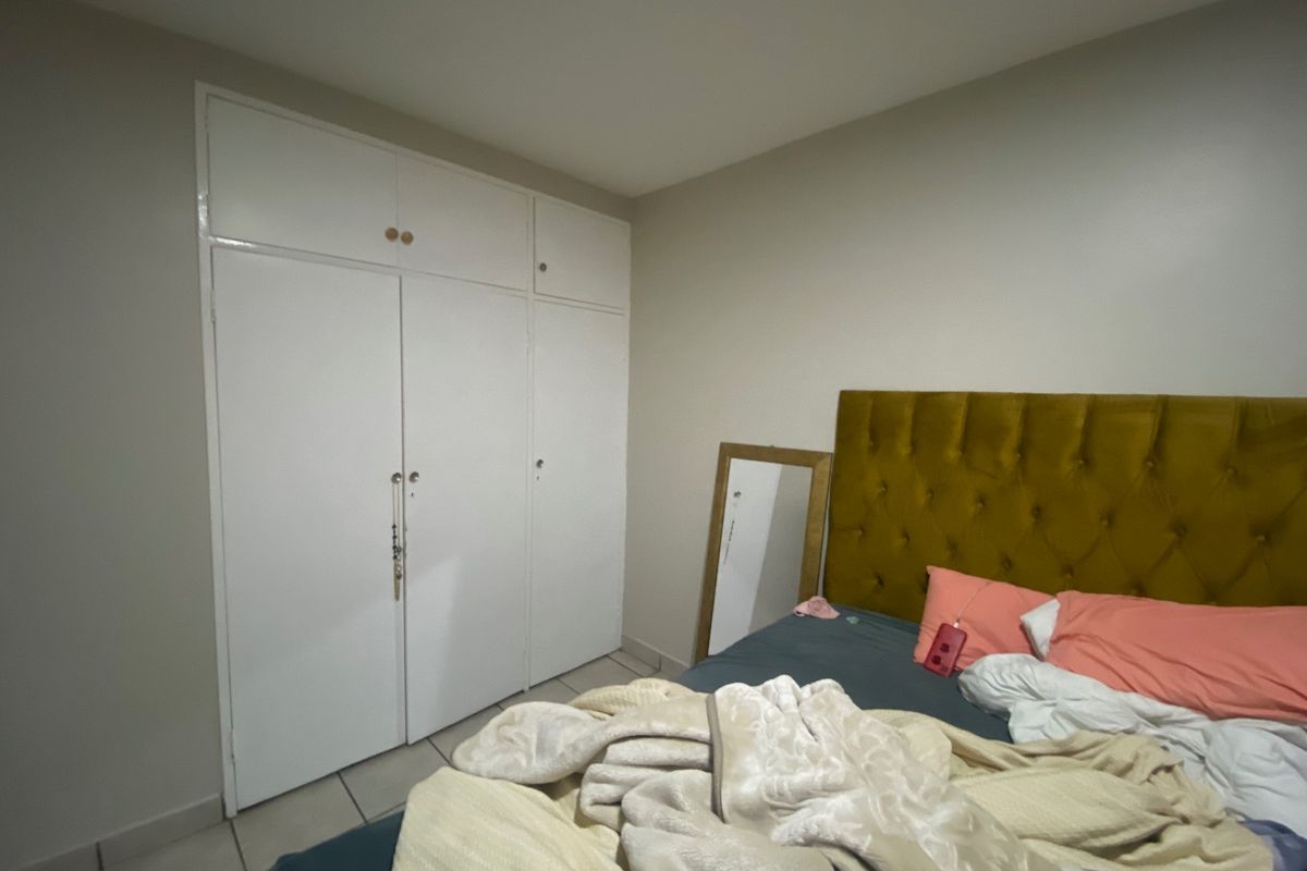 A bedroom featuring built-in cupboards and tiled flooring, providing functional storage space within the room.