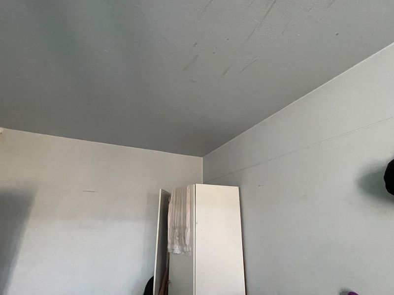 A bedroom interior featuring a built-in wardrobe, showing visible scuff marks and staining on the ceiling surface.