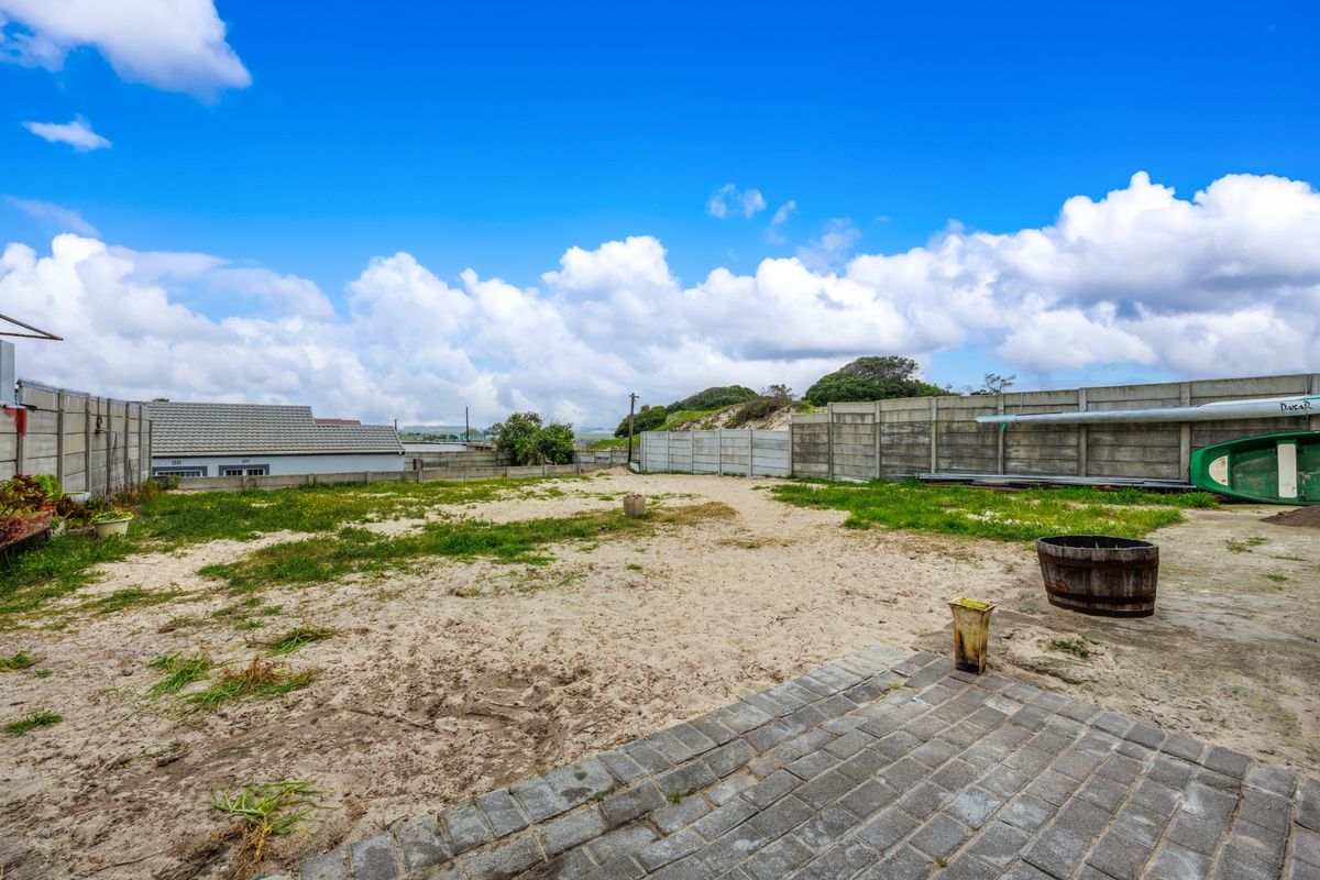 A spacious rear yard featuring a paved patio area and precast concrete boundary walls, offering significant potential for landscaping and outdoor development.