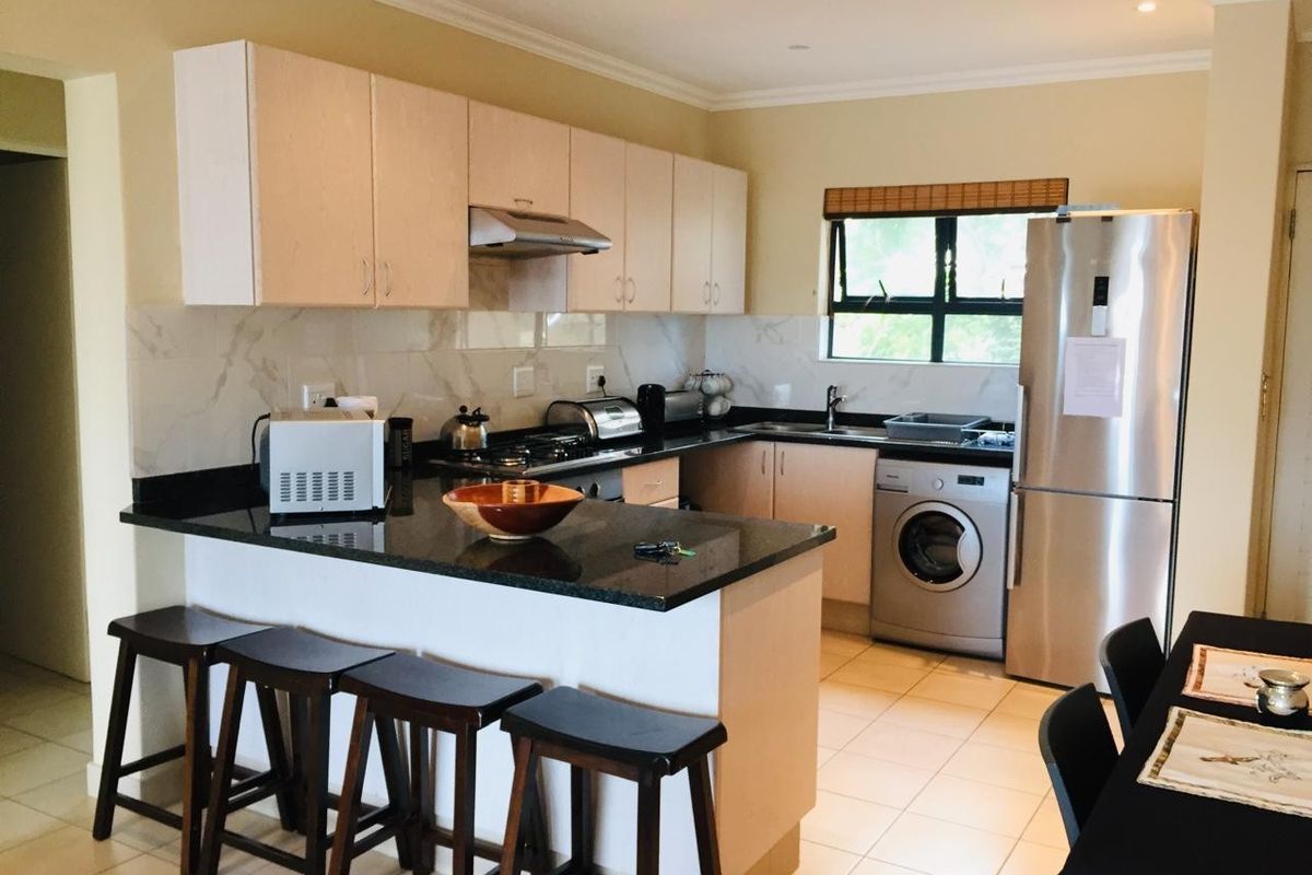 A functional kitchen featuring granite countertops, built-in cabinetry, an integrated extractor fan, and tiled flooring, offering a practical layout for daily use.