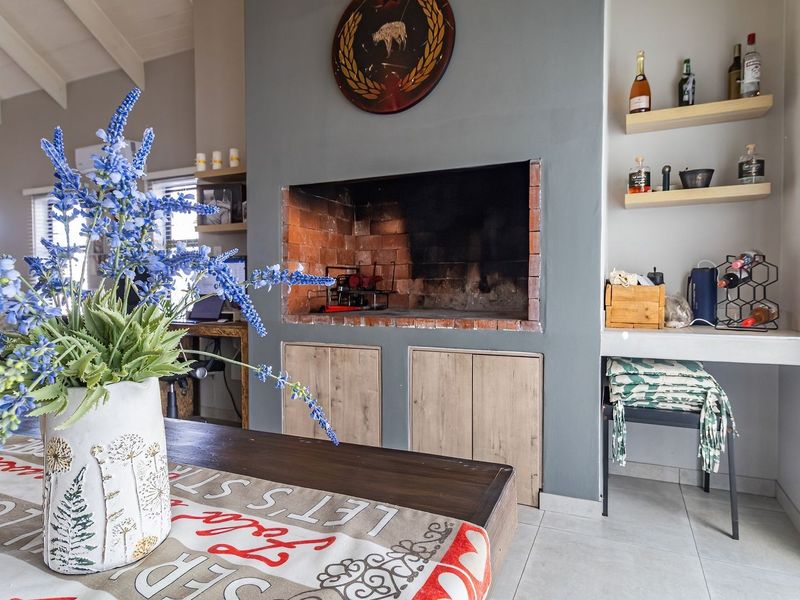 A bright living area featuring a prominent built-in brick fireplace, exposed beam ceilings, and neutral tiled flooring, creating a cozy and inviting atmosphere.