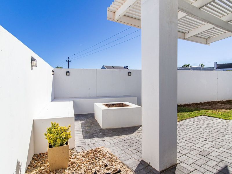A modern outdoor patio area featuring a built-in concrete fire pit, integrated bench seating, and a pergola, perfect for outdoor entertaining.