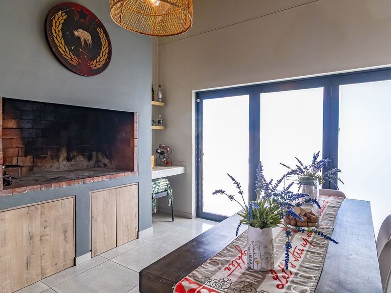 A well-maintained living area featuring a built-in brick fireplace, tiled flooring, and large aluminium sliding doors providing ample natural light.