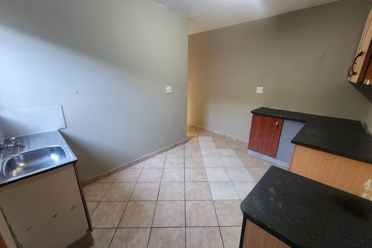 A functional, empty kitchen space featuring tiled flooring, laminate cabinetry, and stone-look countertops, ready for a modern update.