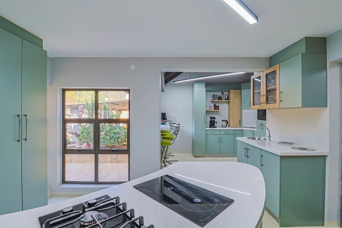 Modern kitchen featuring sage green cabinetry, stone countertops, integrated gas and induction hobs, and a functional layout with a secondary prep area.