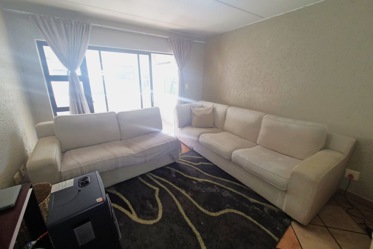 A living room featuring tiled flooring, textured walls, and a large sliding glass door providing access to the outdoor area.