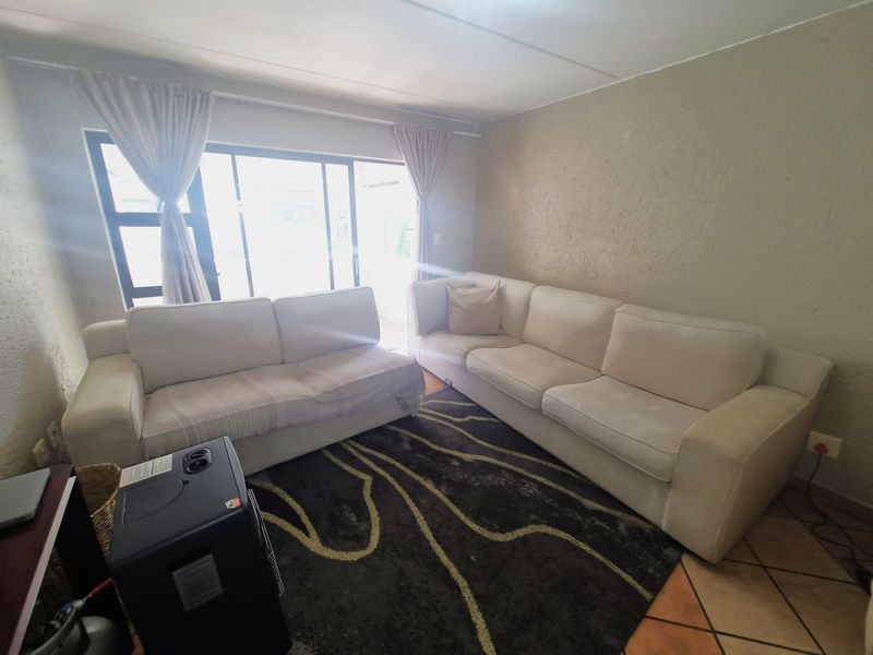 A living room featuring tiled flooring, textured walls, and a large sliding glass door providing access to the outdoor area.