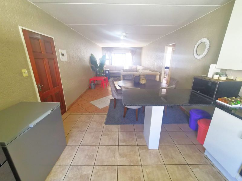 Open-plan living and dining area featuring a kitchen with a granite breakfast bar and tiled flooring throughout.