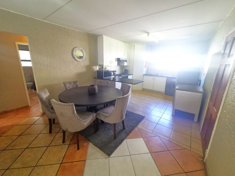 Open-plan kitchen and dining area featuring tiled flooring and built-in cabinetry, providing a functional space for cooking and meals.