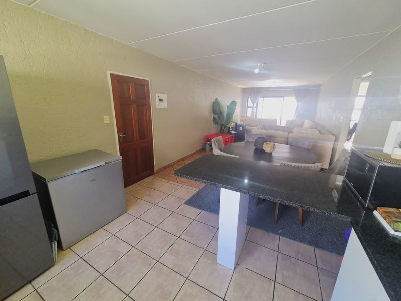Open-plan living and kitchen area featuring tiled flooring, a granite breakfast bar, and direct access to the living space.