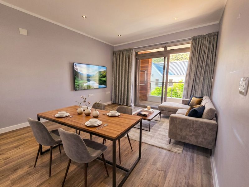 A modern open-plan living and dining area featuring laminate flooring, recessed lighting, and a sliding glass door leading to a private balcony.