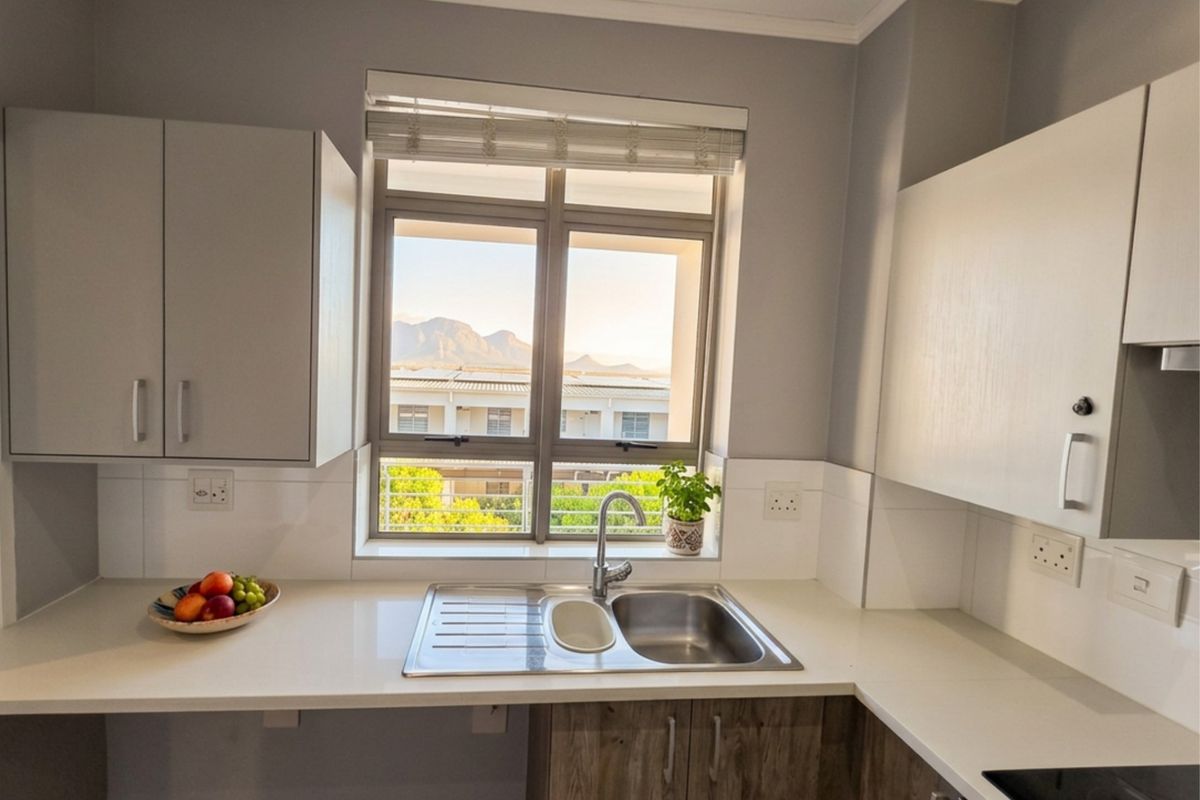A modern kitchen featuring quartz countertops, stainless steel sink, and ample cabinetry, with a window offering pleasant mountain views.