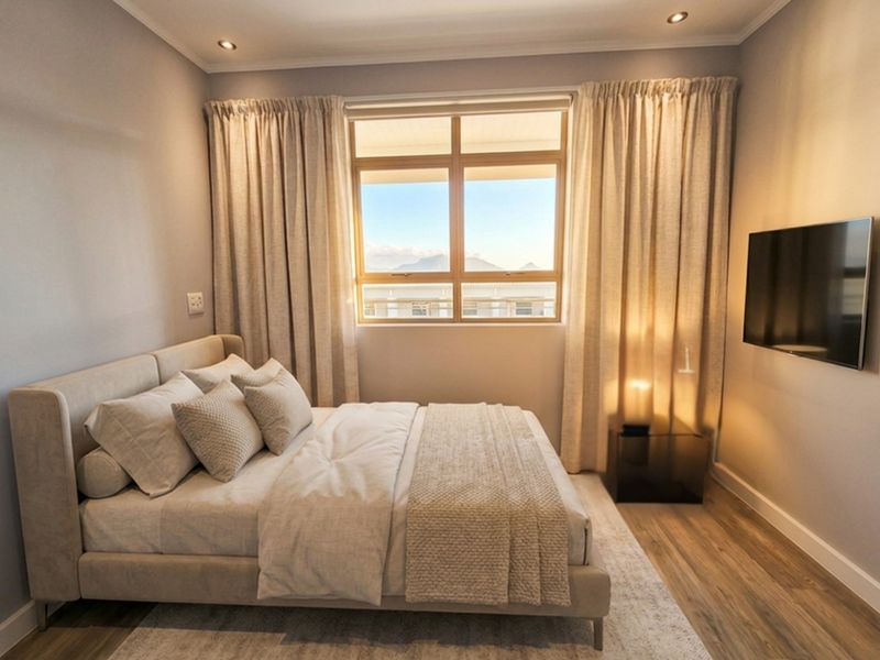 A well-maintained bedroom featuring laminate flooring, recessed downlighting, and a large window with natural light and mountain views.