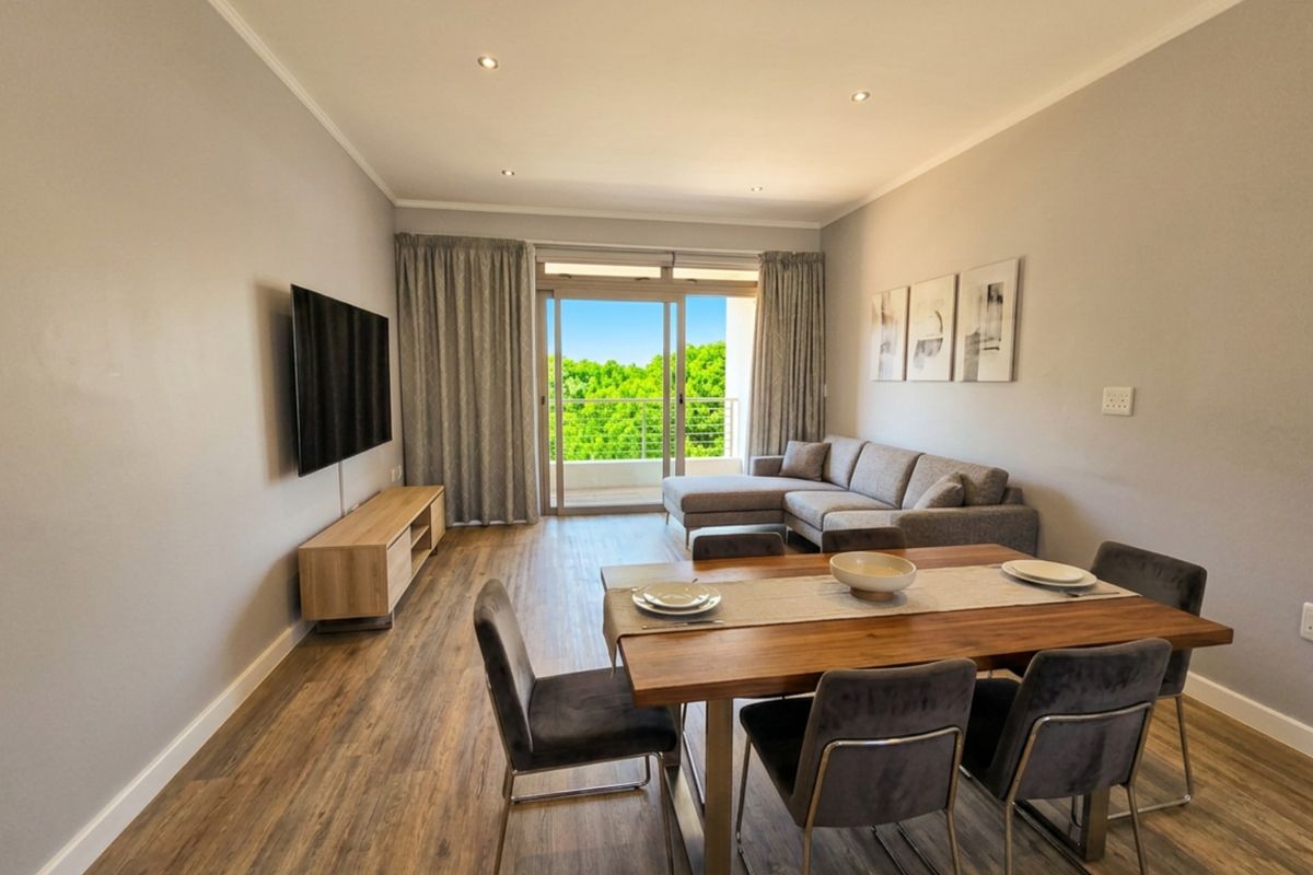 Open-plan living and dining area featuring laminate flooring, recessed lighting, and direct access to a private balcony through sliding glass doors.