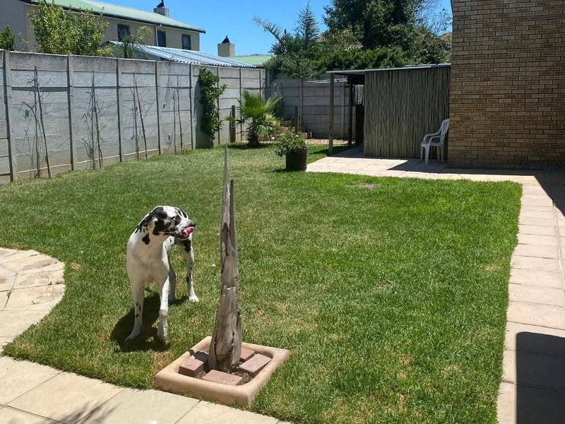 A private rear garden featuring a well-maintained lawn, paved patio area, and secure precast concrete boundary walls.