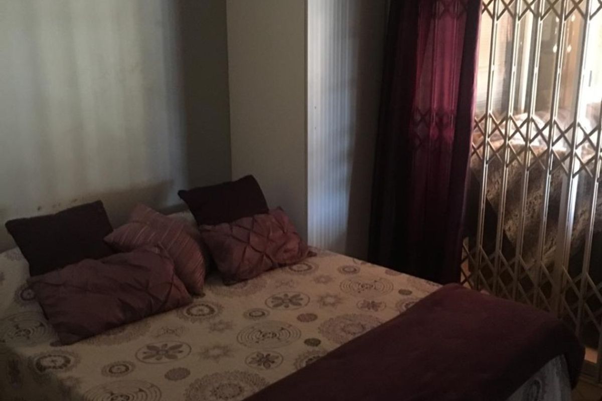 A bedroom featuring built-in cupboards and a security gate leading to an outdoor area.