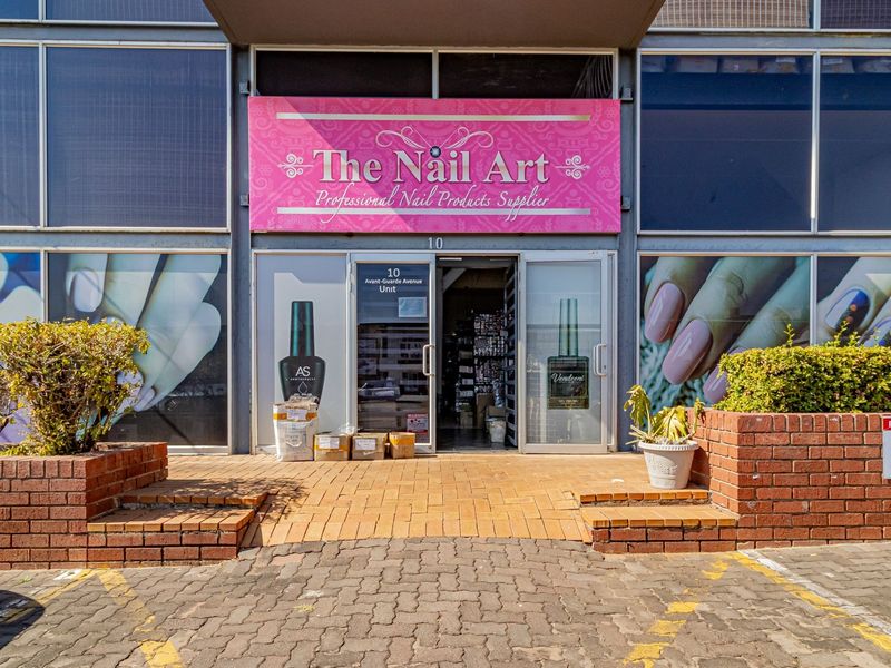Commercial storefront entrance featuring aluminium framed glass facade, brick planter boxes, and prominent business signage.