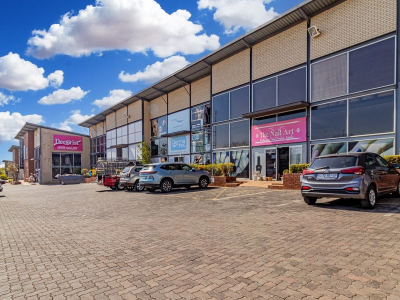 Front view of a commercial retail complex featuring paved parking, large glass storefronts, and modern brick and metal construction.