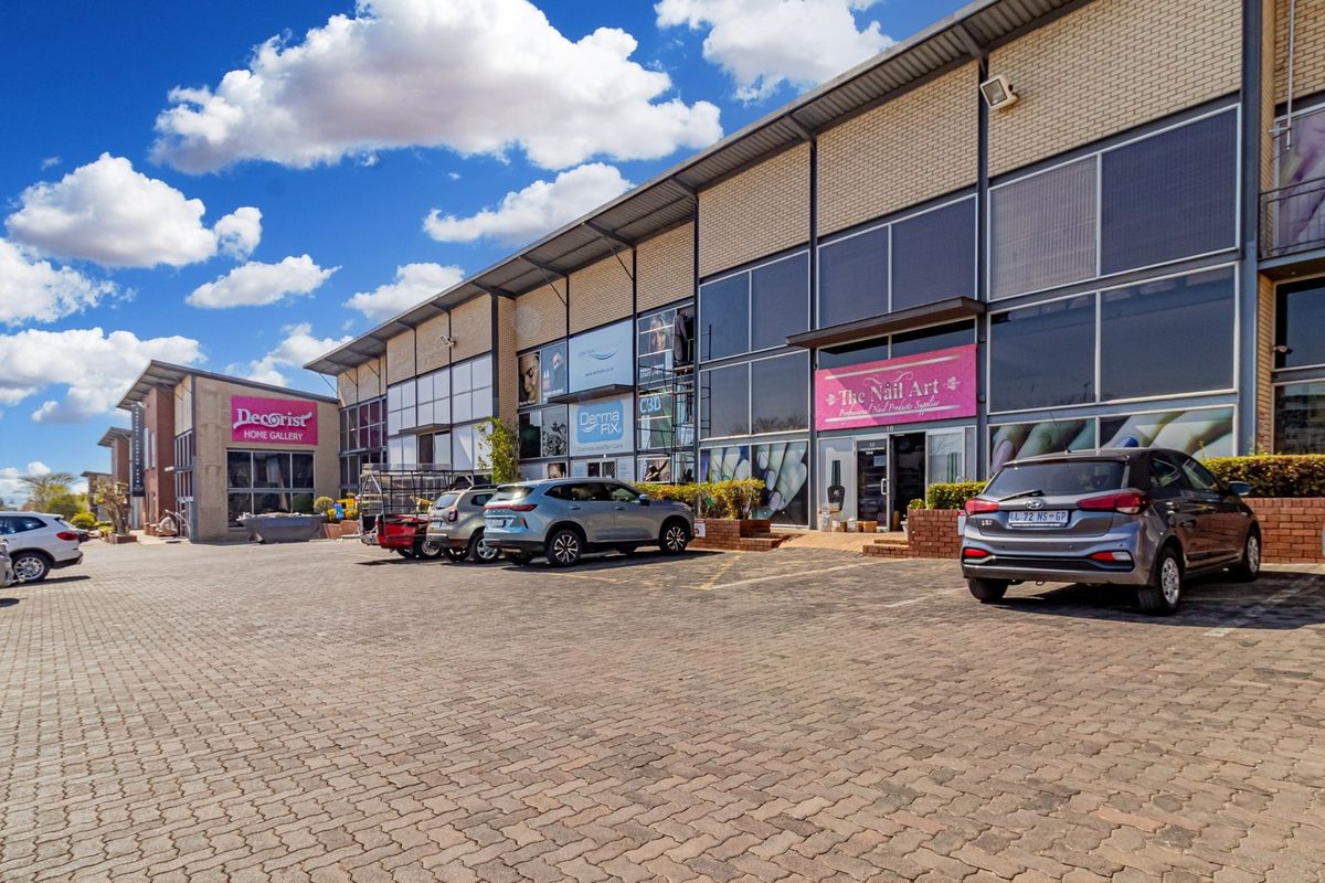 Front view of a commercial retail complex featuring paved parking, large glass storefronts, and modern brick and metal construction.