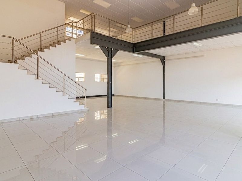 Spacious open-plan commercial unit featuring a mezzanine level, tiled flooring, and a modern steel staircase with stainless steel balustrades.