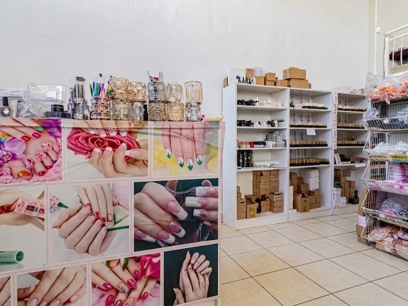 A commercial retail space featuring tiled flooring and multiple built-in shelving units, currently utilized for beauty supply storage and display.