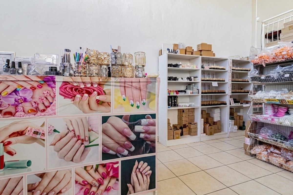 A commercial retail space featuring tiled flooring and multiple built-in shelving units, currently utilized for beauty supply storage and display.