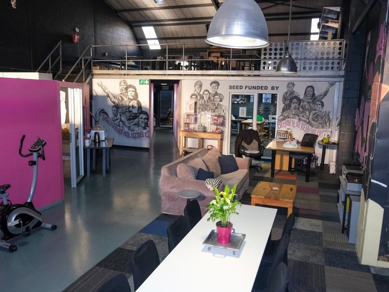 Spacious industrial open-plan area featuring a mezzanine level, exposed steel trusses, and durable epoxy flooring, suitable for a creative workspace or studio.