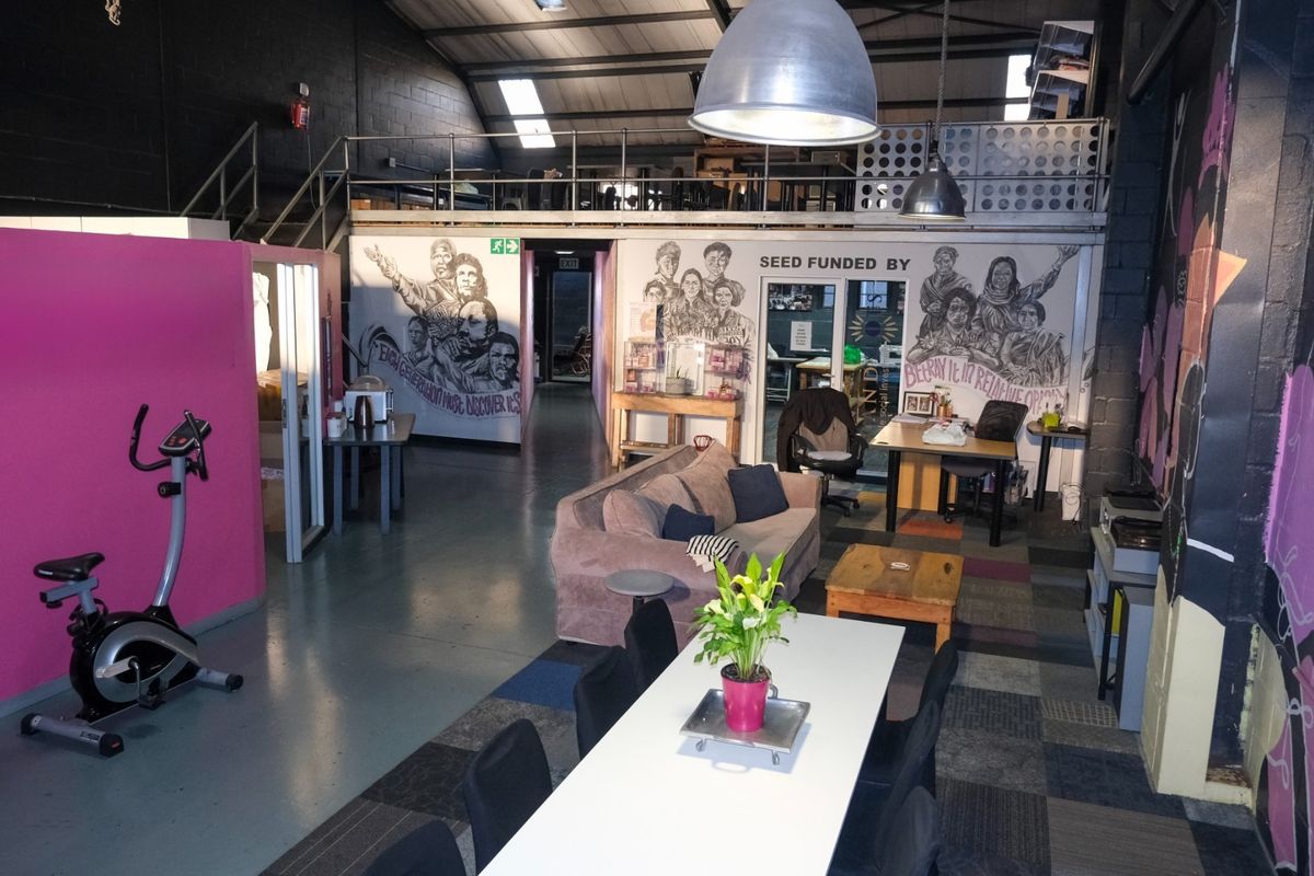Spacious industrial open-plan area featuring a mezzanine level, exposed steel trusses, and durable epoxy flooring, suitable for a creative workspace or studio.