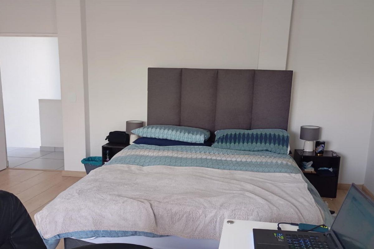 A functional bedroom featuring laminate flooring and neutral wall finishes, providing a comfortable space for rest.