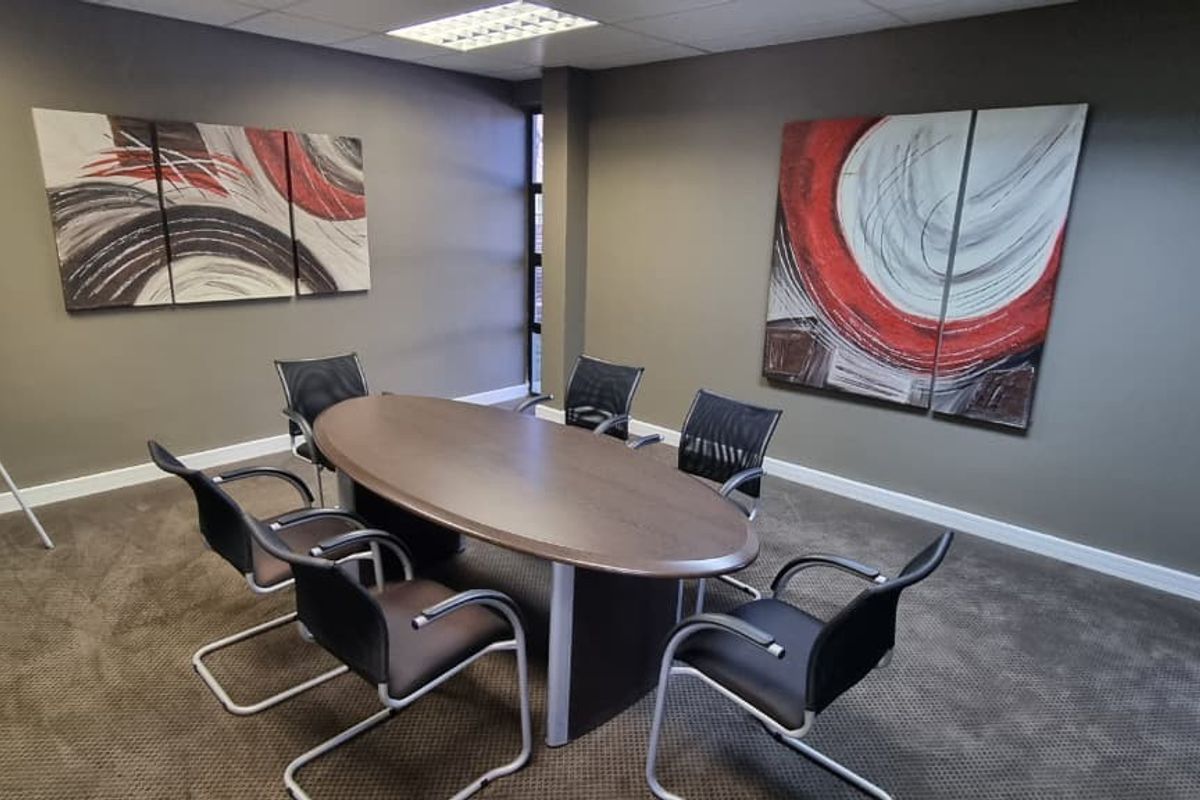 A professional office meeting room featuring neutral wall tones, recessed ceiling lighting, and carpeted flooring, suitable for collaborative work or client meetings.