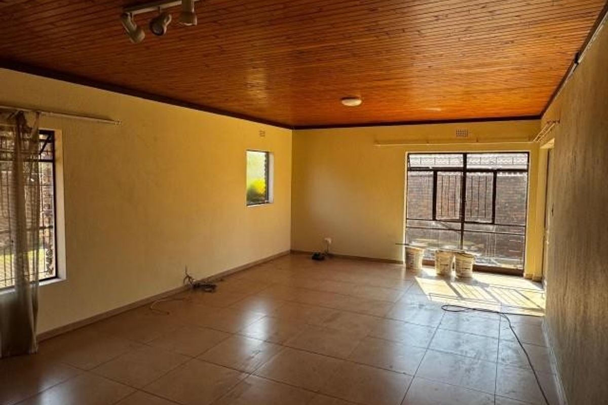Spacious living area featuring a timber tongue and groove ceiling, tiled flooring, and large sliding glass doors leading to the exterior.