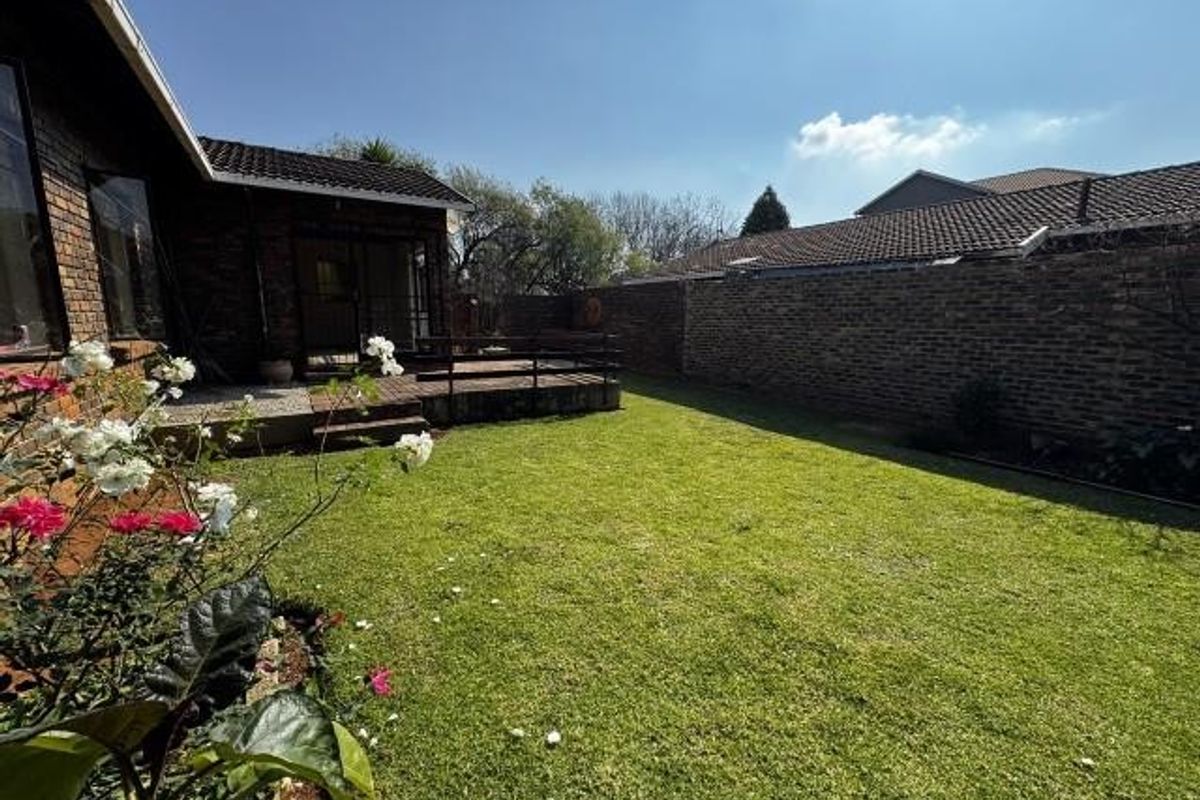 A private rear garden featuring a well-maintained lawn, a paved patio area, and secure brick boundary walls.