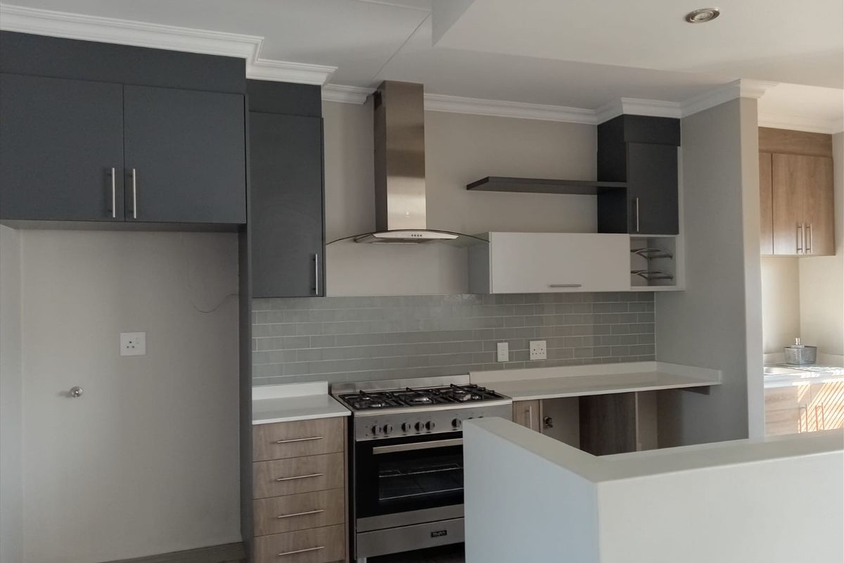Modern kitchen featuring two-tone cabinetry, gas stove with stainless steel extractor fan, subway tile backsplash, and quartz countertops.