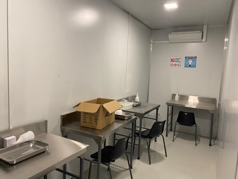 A clean, functional utility or prep space featuring stainless steel work surfaces, integrated air conditioning, and durable wall paneling suitable for industrial or farm use.