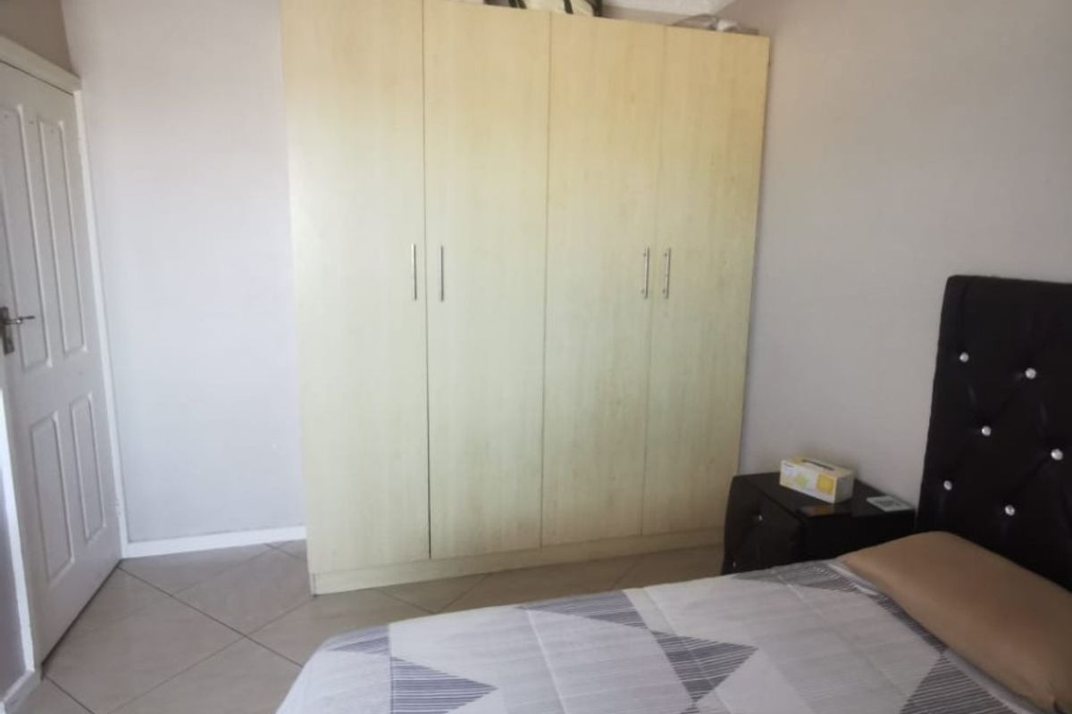 A bedroom featuring neutral walls, tiled flooring, crown molding, and a built-in wardrobe providing ample storage space.