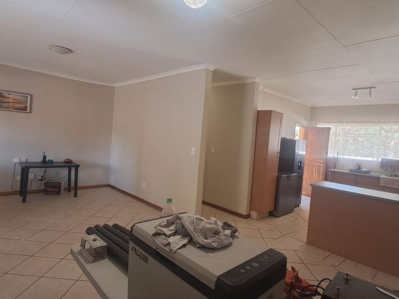 Open-plan living and kitchen area featuring tiled flooring and functional cabinetry, offering a versatile space ready for modernization and personal styling.