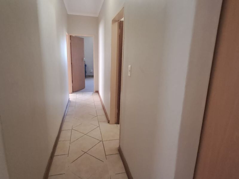A clean, neutral hallway featuring tiled flooring and access to multiple rooms, providing a functional transition space within the home.
