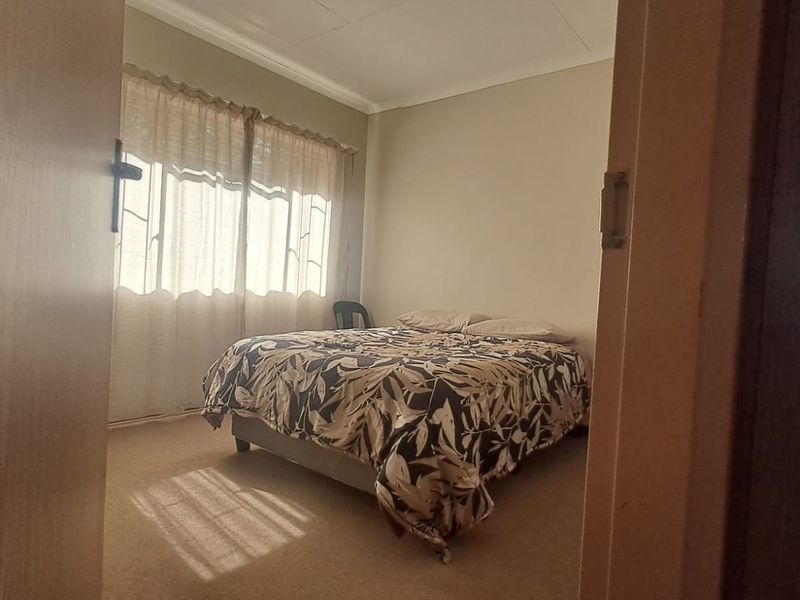 A standard bedroom featuring carpeted flooring and natural light through window treatments.